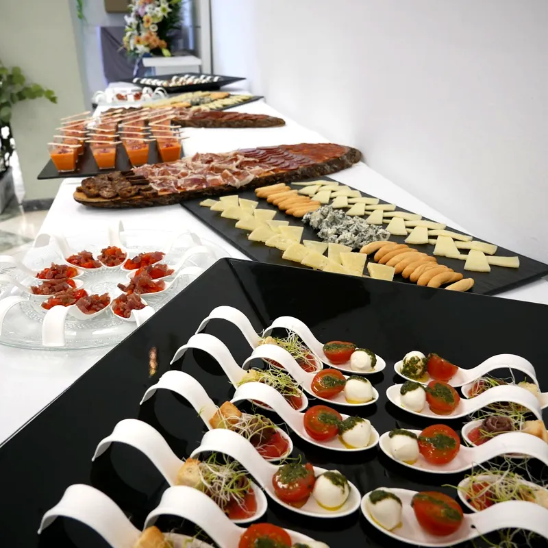 Bandejas de catering con canapés y embutidos sobre una mesa negra