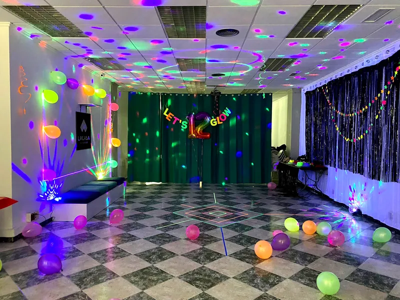 Fiesta de cumpleaños con luces de neón, globos y la sala a oscuras