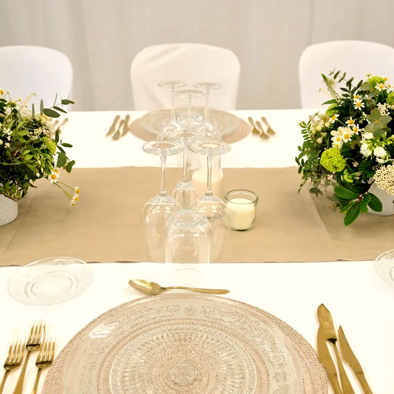 Mesa con bajoplatos dorados, copas y flores blancas