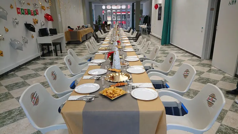 Mesa corrida con mantel y platos servidos para una comida en grupo