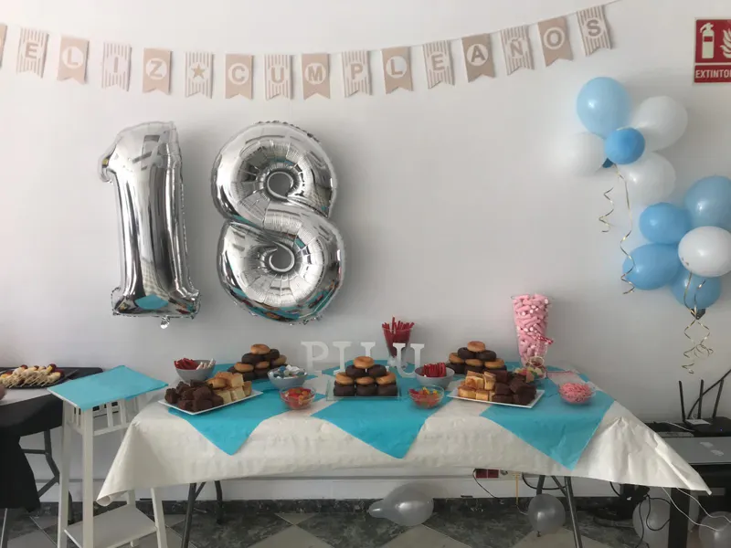 Mesa dulce de un 18 cumpleaños con globos plateados y guirnalda de feliz cumpleaños