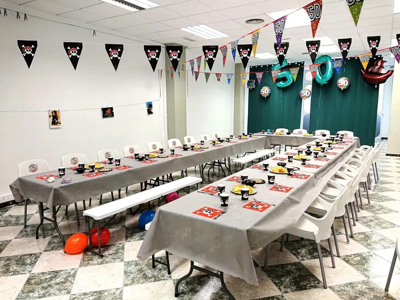 Mesas preparadas para una fiesta de 50 cumpleaños con banderines y globos en la sala de Lacasa