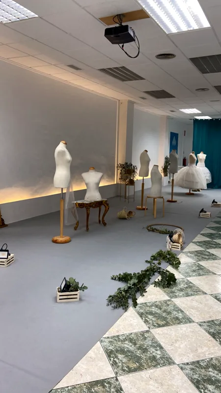 Sala de Lacasa preparada para la exposición, con maniquíes, flores y luz indirecta en la pared