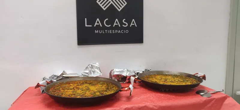 Dos paellas sobre una mesa con mantel rojo bajo el cartel de Lacasa